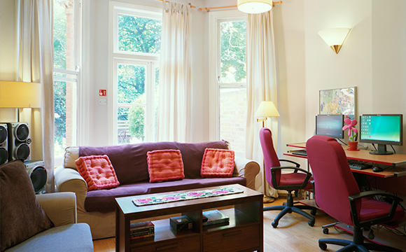 cozy living room with two computers and a comfortable sofa featuring cushions natural light and inviting atmosphere