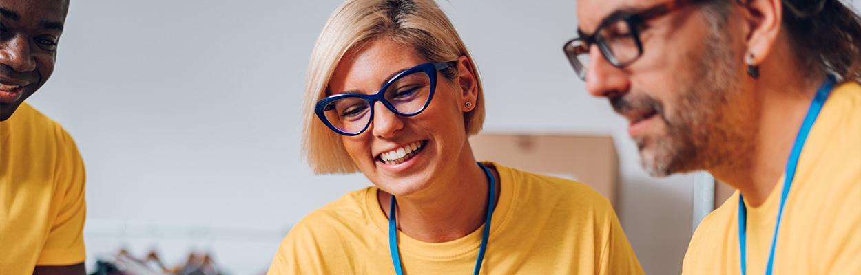 three people collaborating joyfully in yellow t-shirts while engaged in active discussion about teamwork and ideas for two projects