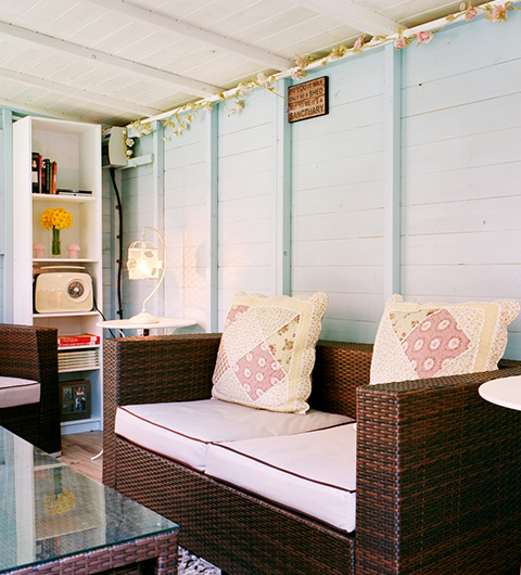 cozy interior of a rustic garden shed featuring a glass table woven furniture colorful pillows and shelves with books and flowers ideal sanctuary for relaxation